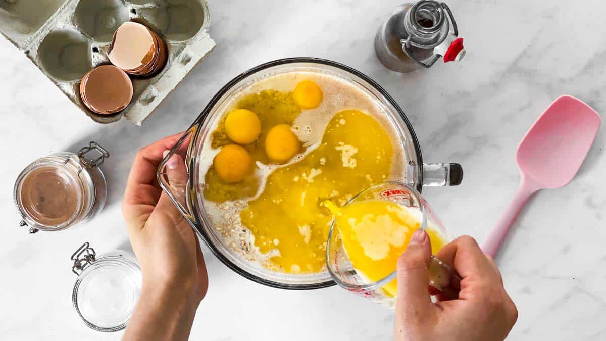 pouring melted butter into bowl with eggs and oats