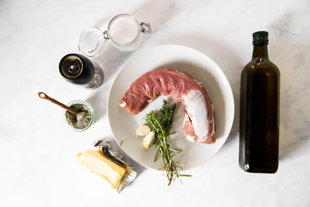 ingredients to make pork tenderloin on white marble surfacer