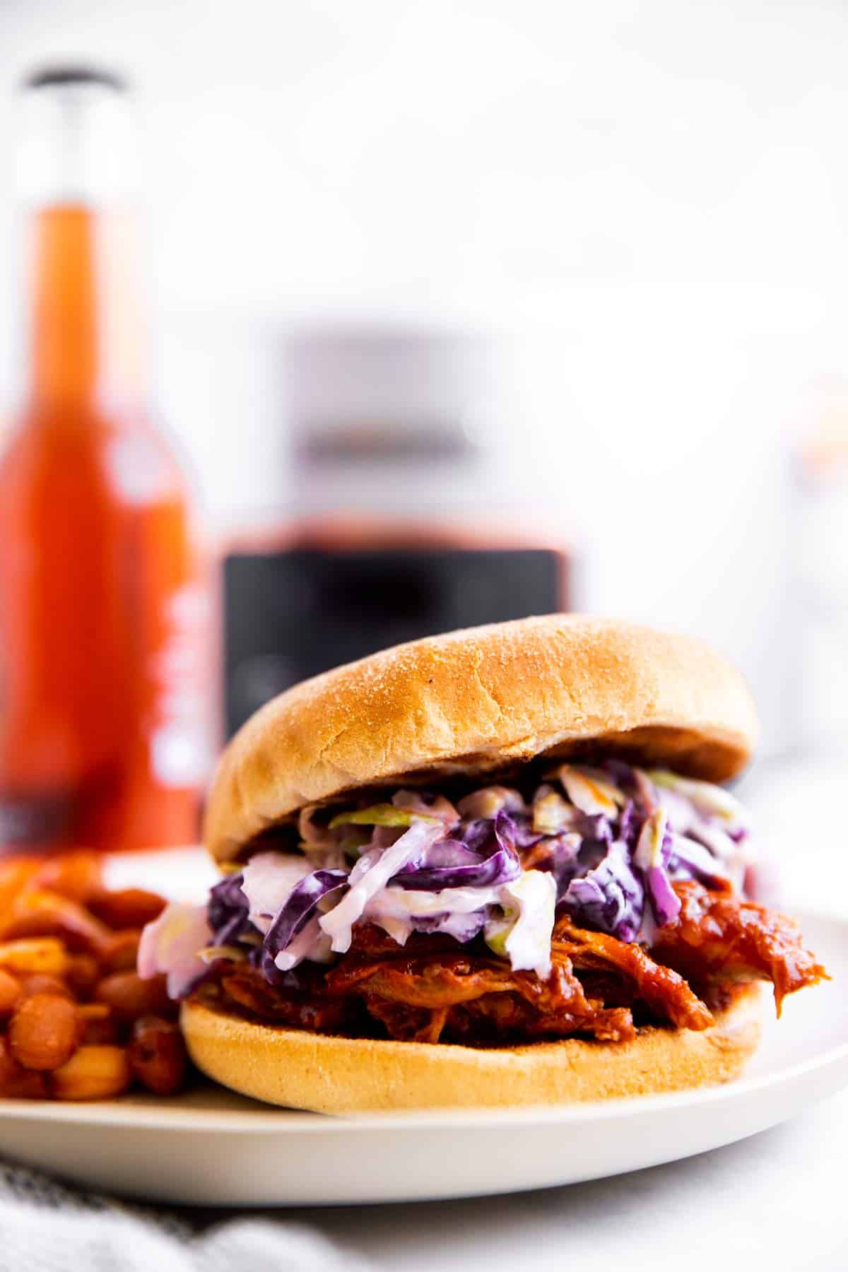 pulled pork sandwich with beer and crockpot in background
