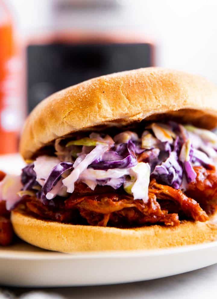 pulled pork sandwich with beer and crockpot in background