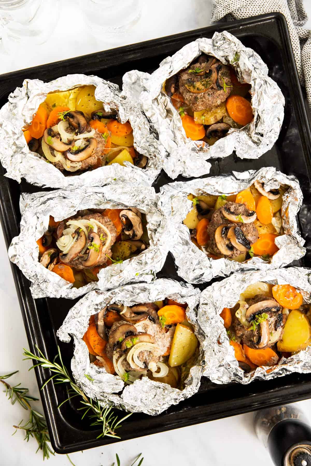 overhead view of baking sheet with six hobo dinner foil packets