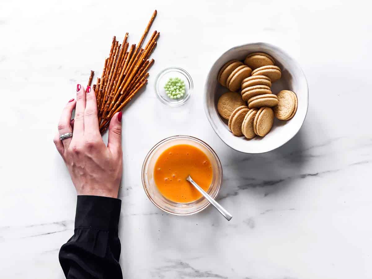 ingredients to make pumpkin decorated Oreos on marble counter