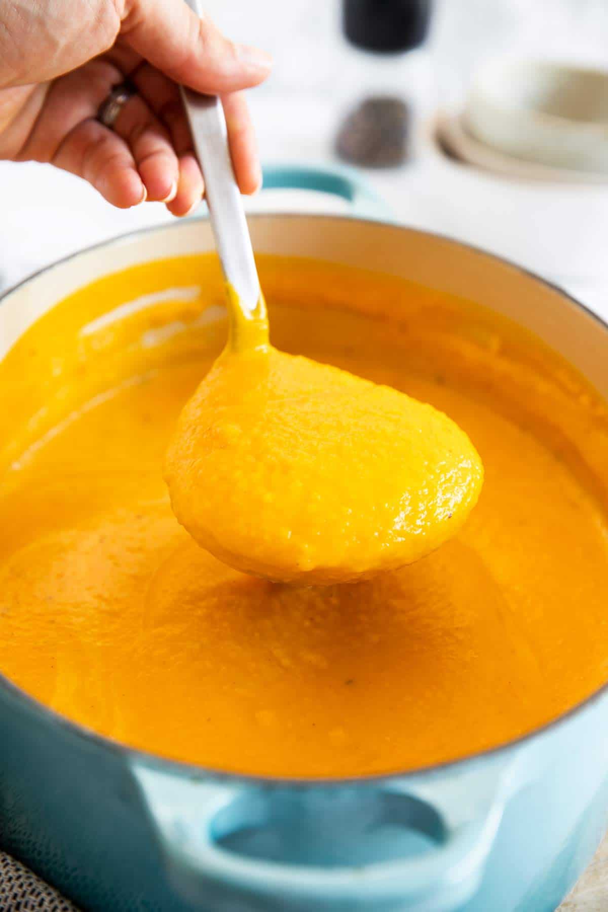 ladle of butternut squash soup over full pot