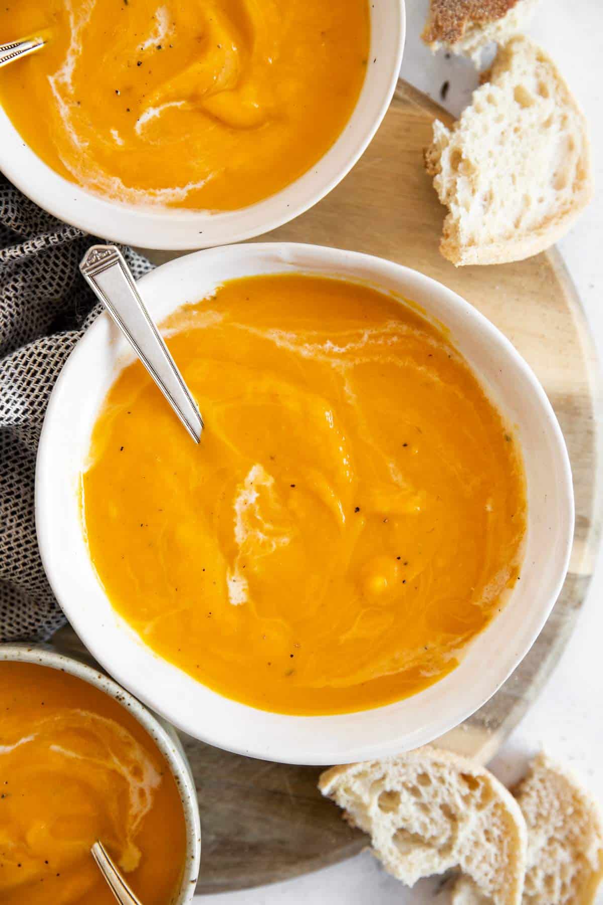 bowls with butternut squash soup next to white bread