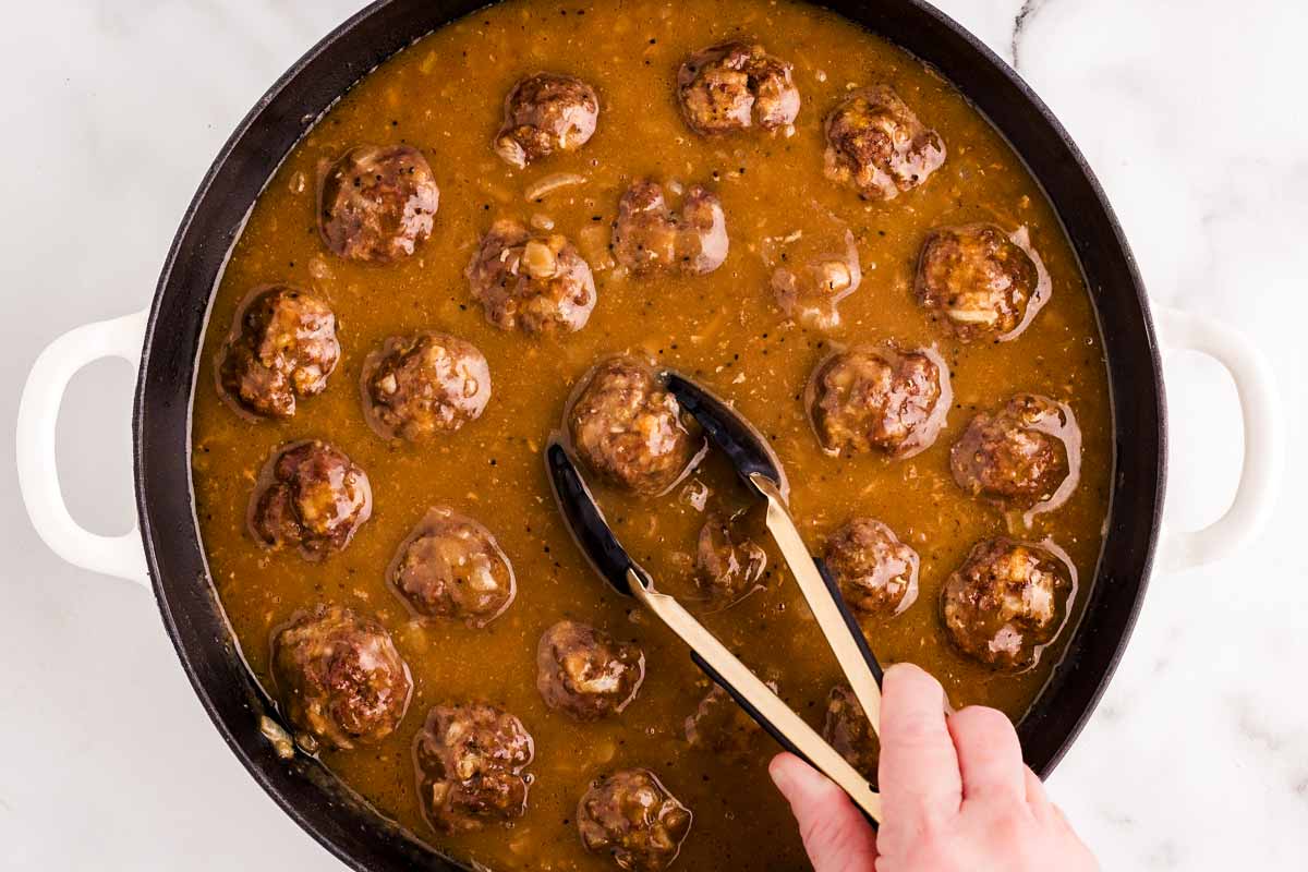 Adding meatball to gravy.