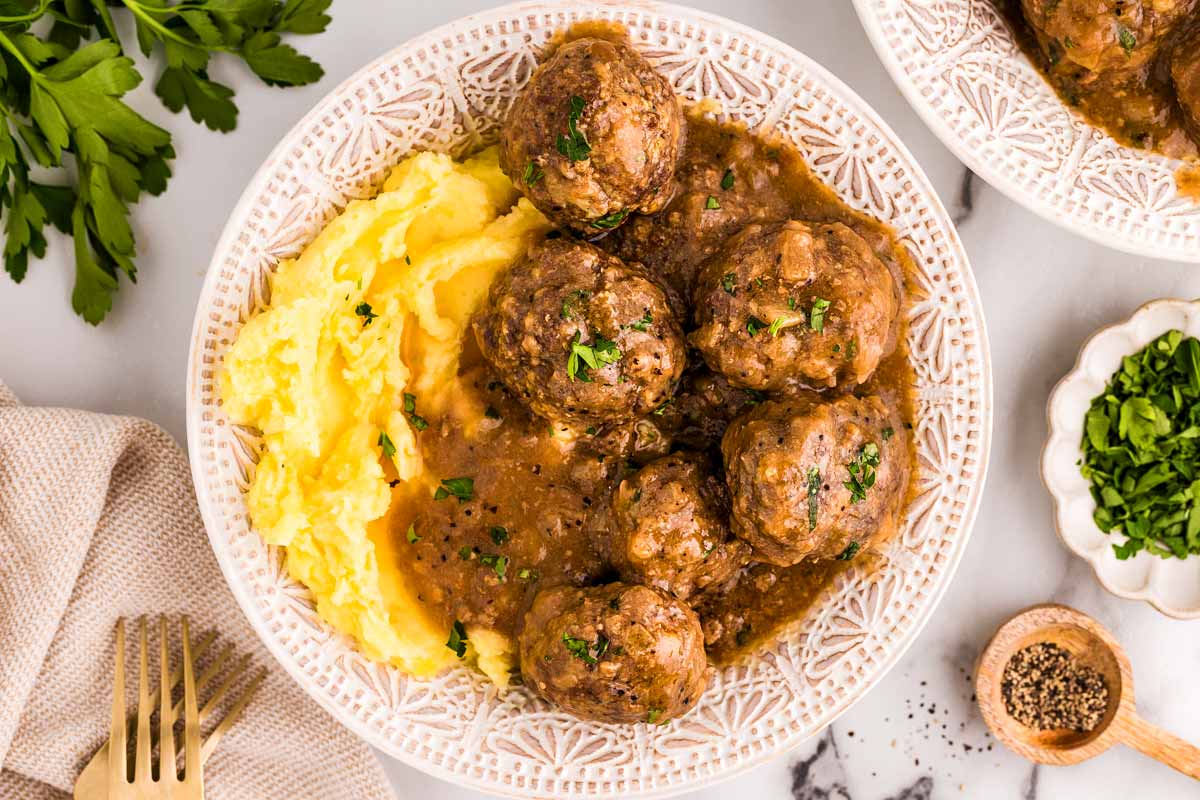 Meatballs in gravy with mashed potatoes on a plate.