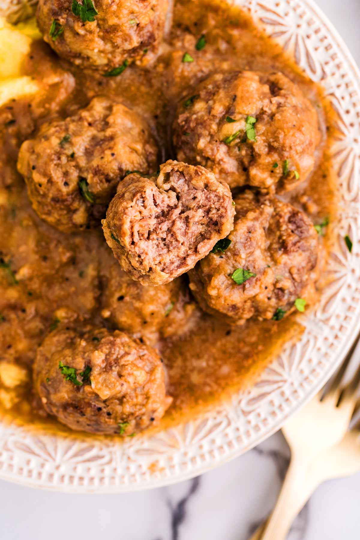 Meatballs in brown gravy on a plate.