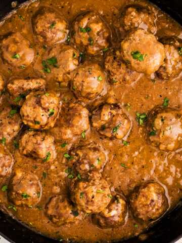 Meatballs in gravy in a skillet.