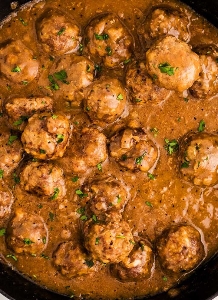Meatballs in gravy in a skillet.