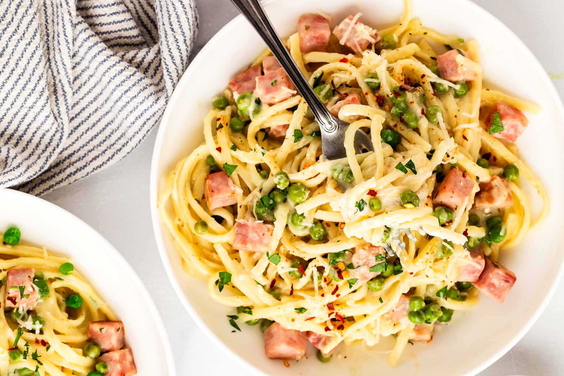 Serving plates of ham and pea pasta.