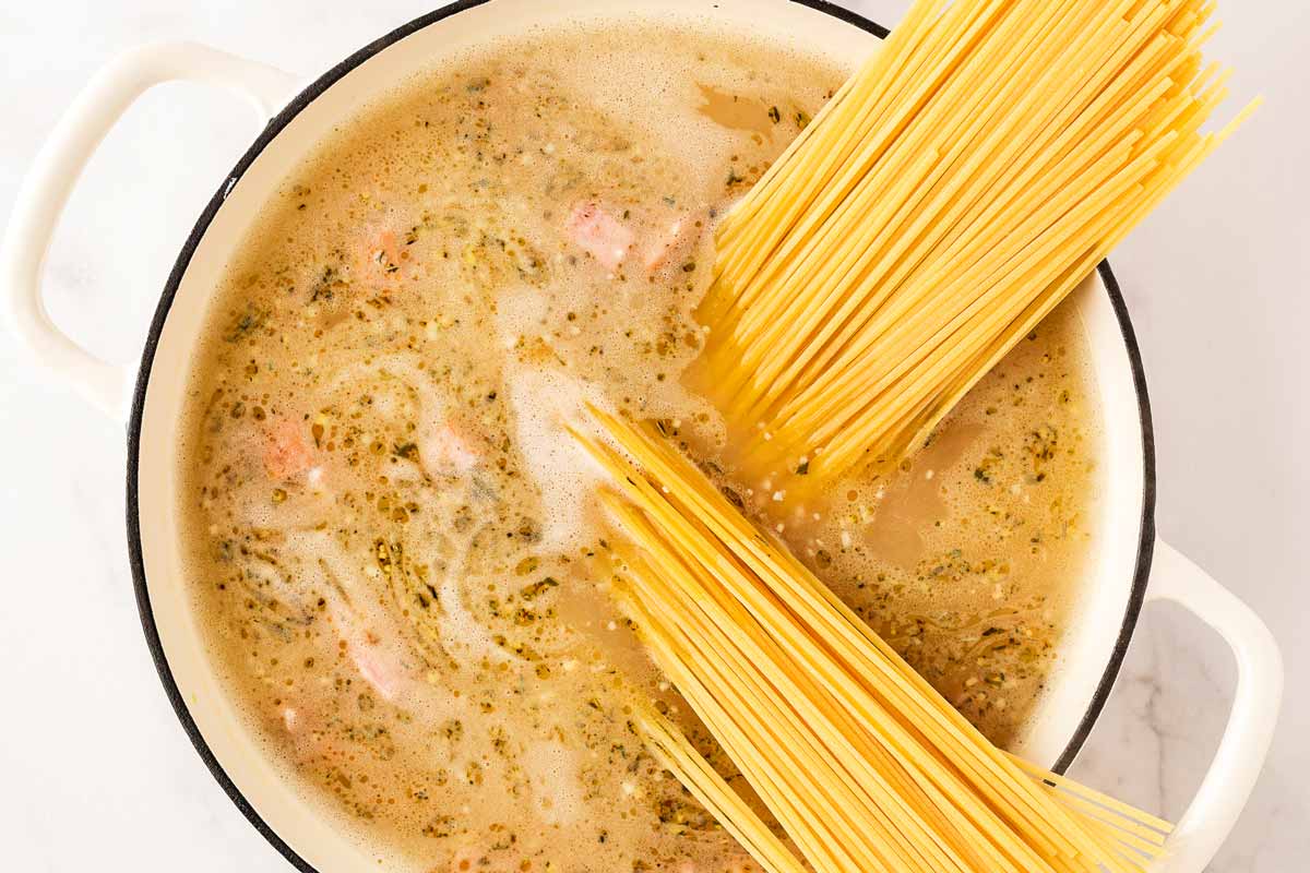 Adding linguine to pot with both and ham cubes.