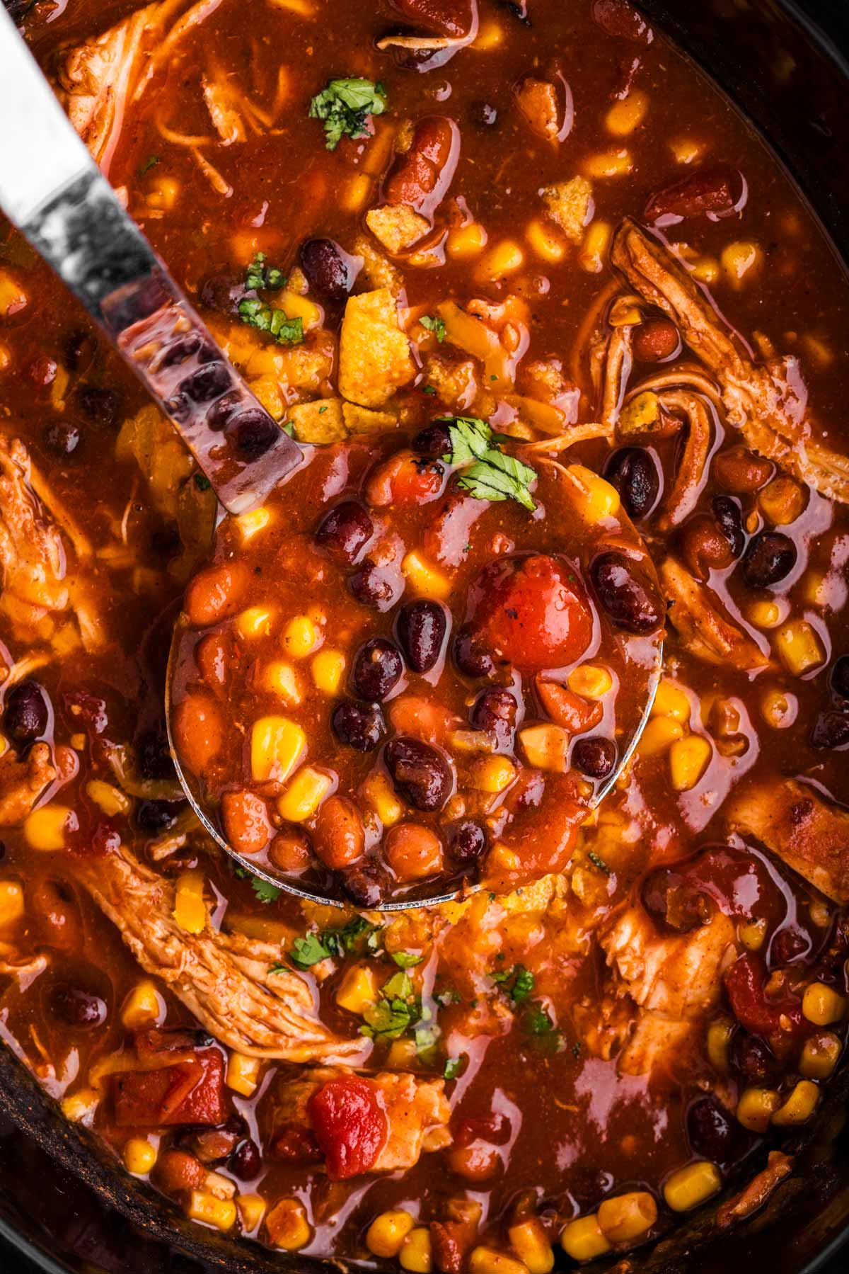 Scooping up chicken taco soup with a ladle.