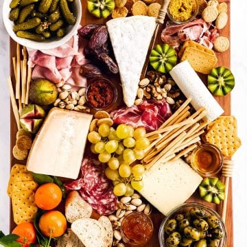 overhead view of a charcuterie board with various cold cuts, cheeses and nibbles