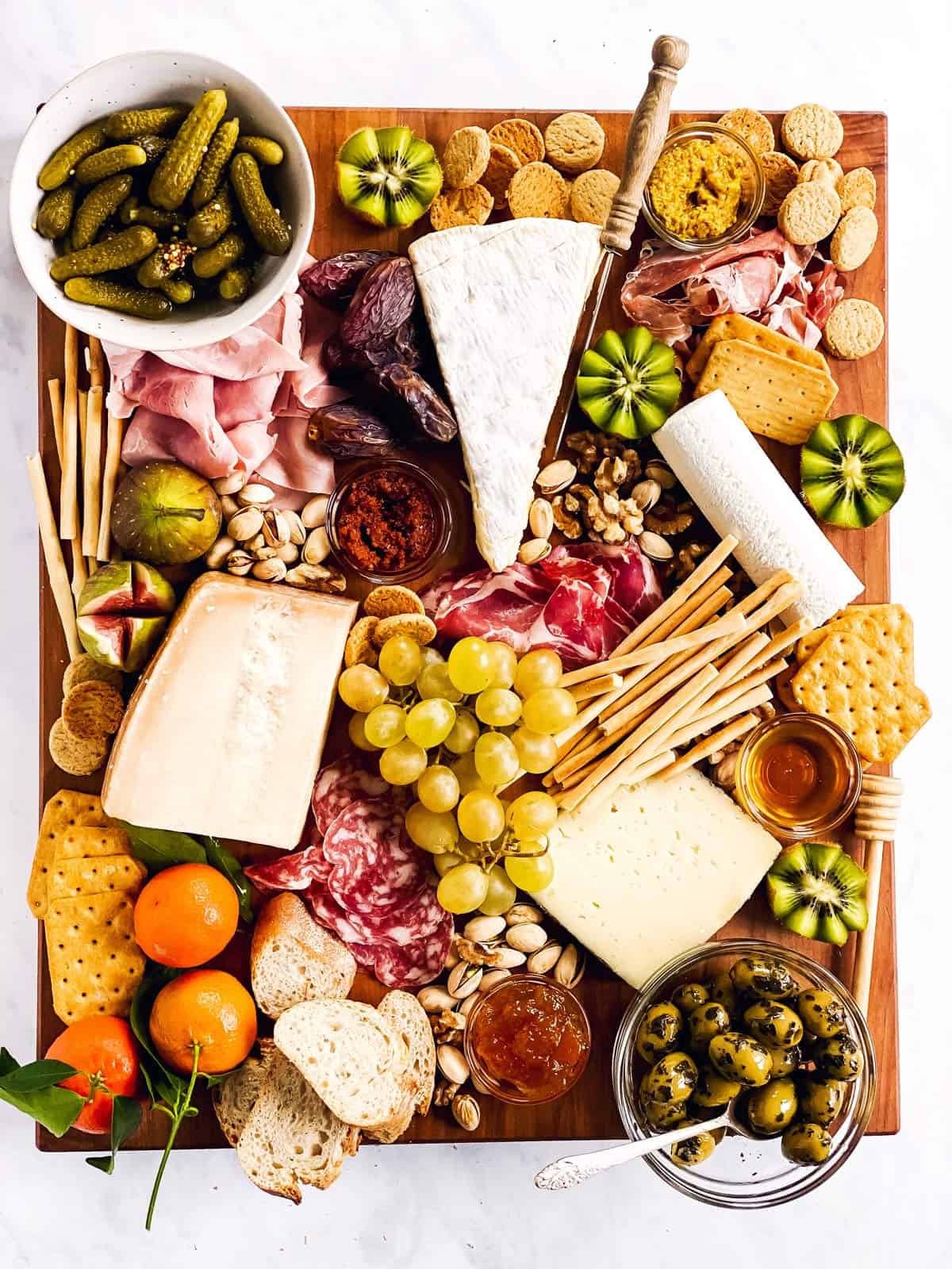 overhead view of a charcuterie board with various cold cuts, cheeses and nibbles