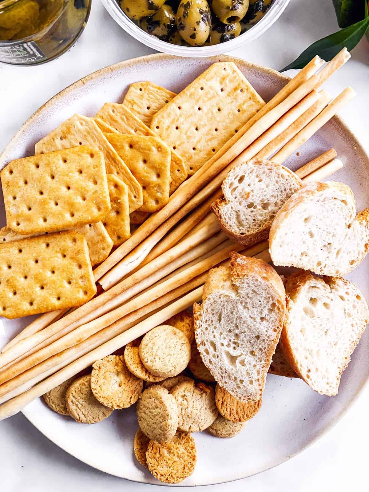 several crackers and sliced baguette on white plate