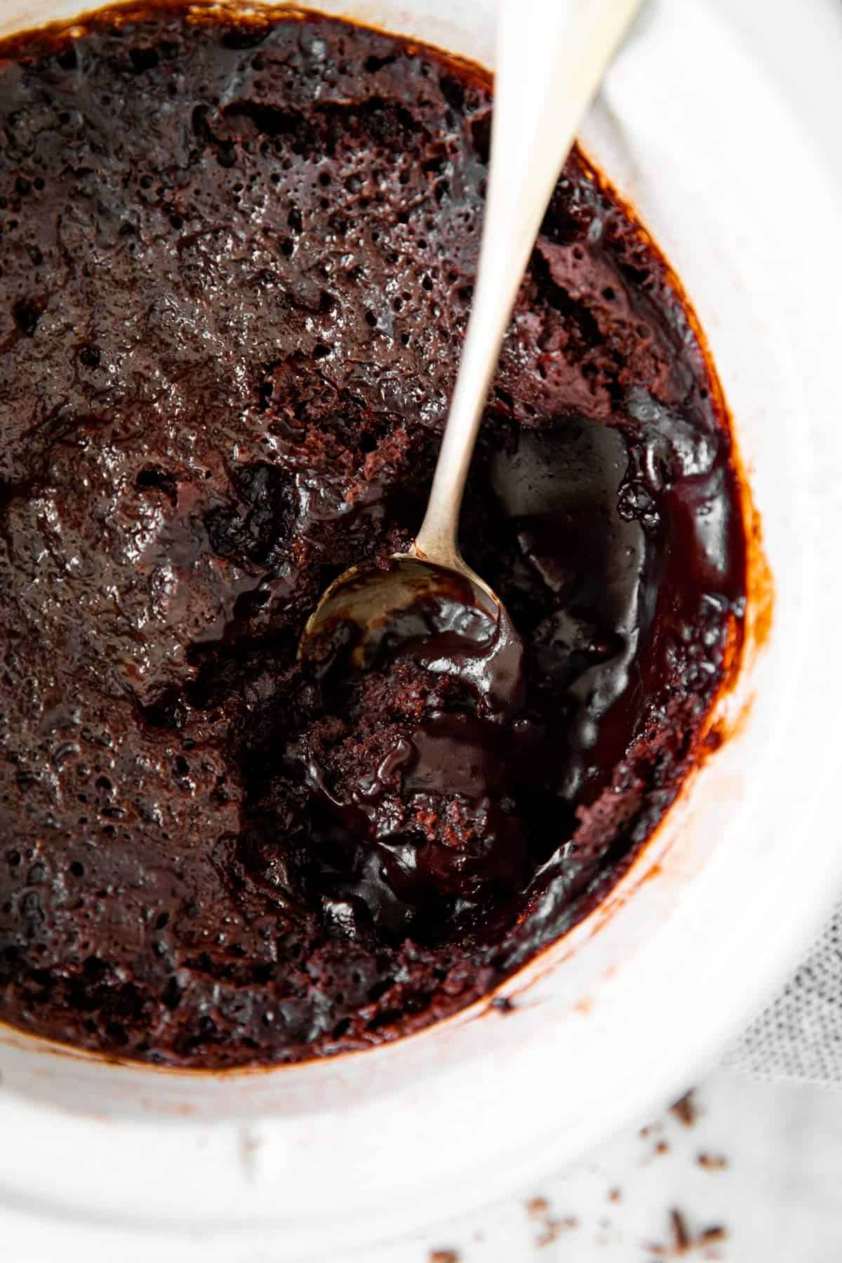 overhead closeup of chocolate pudding cake in white crock with spoon