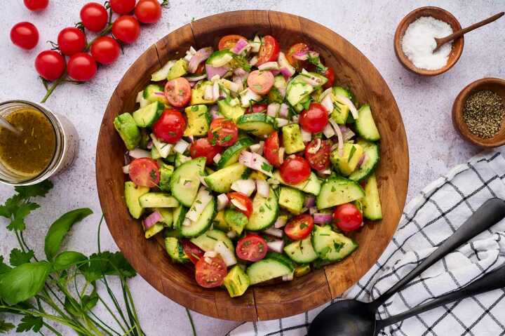 cucumber tomato avocado salad in wooden bowl