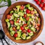 cucumber tomato avocado salad in wooden bowl