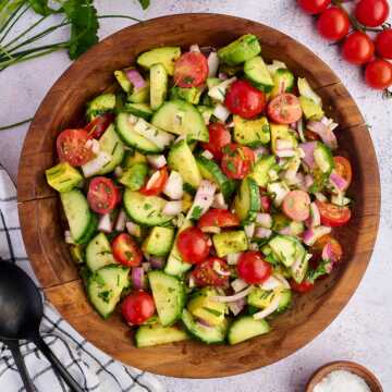 cucumber tomato avocado salad in wooden bowl