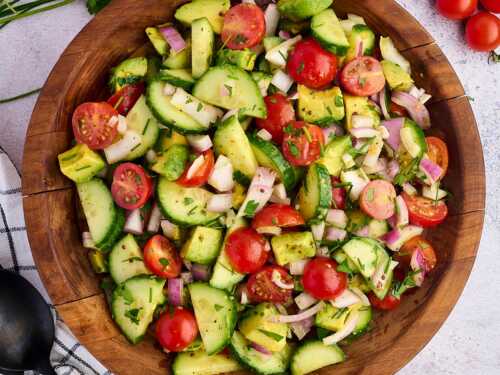 cucumber tomato avocado salad in wooden bowl