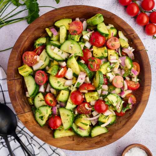 cucumber tomato avocado salad in wooden bowl