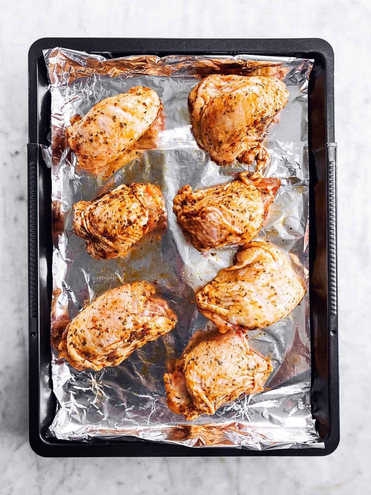 baking pan with seasoned chicken thighs