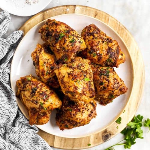 overhead view of plate on wooden platter with chicken thighs