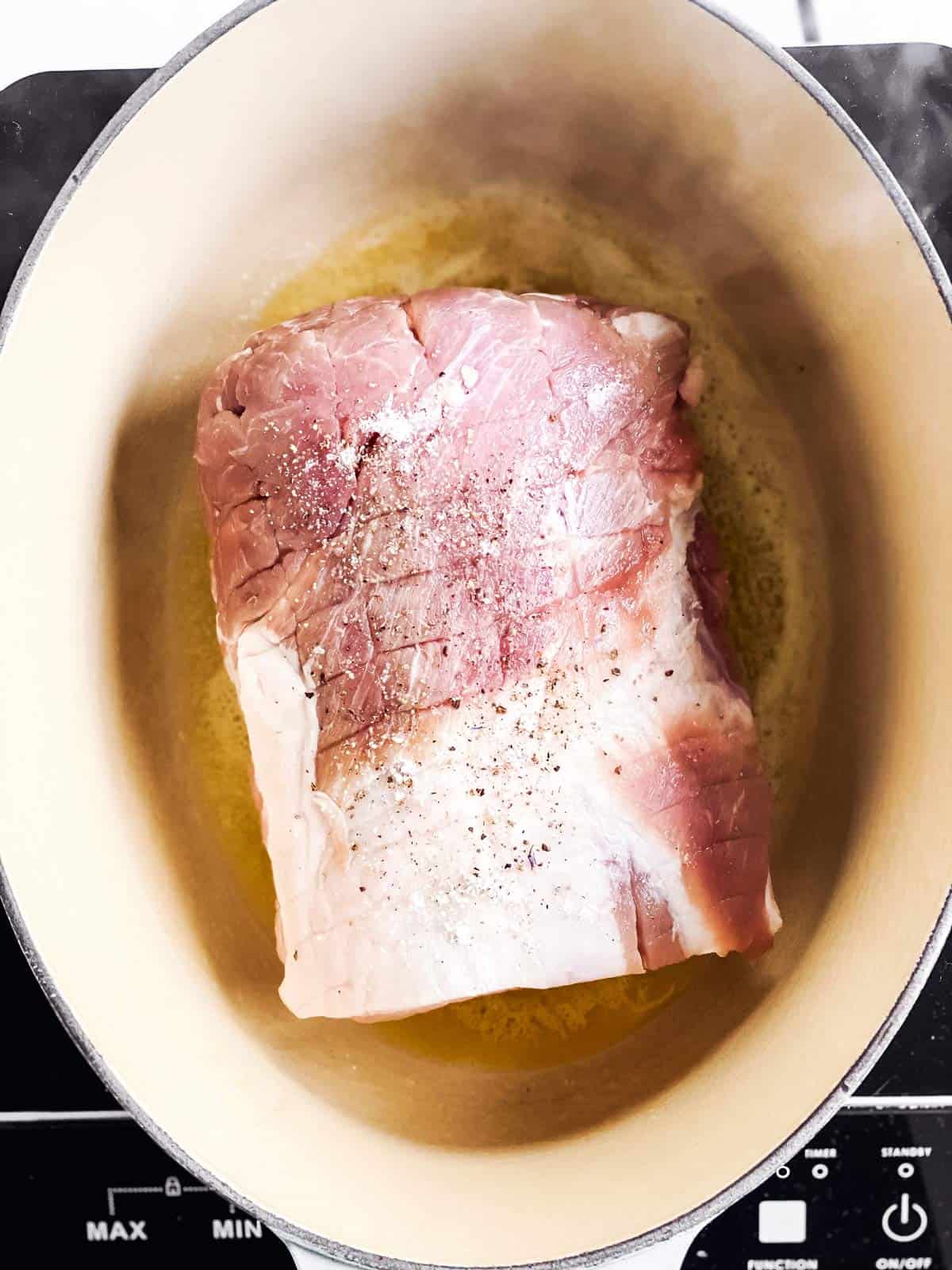 raw pork roast in dutch oven with butter