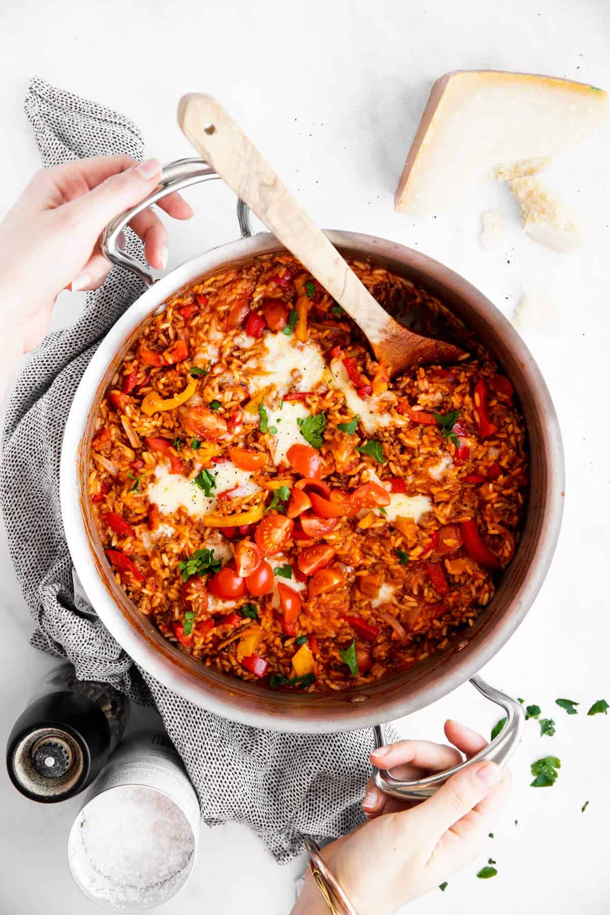 female hands holding skillet with unstuffed peppers