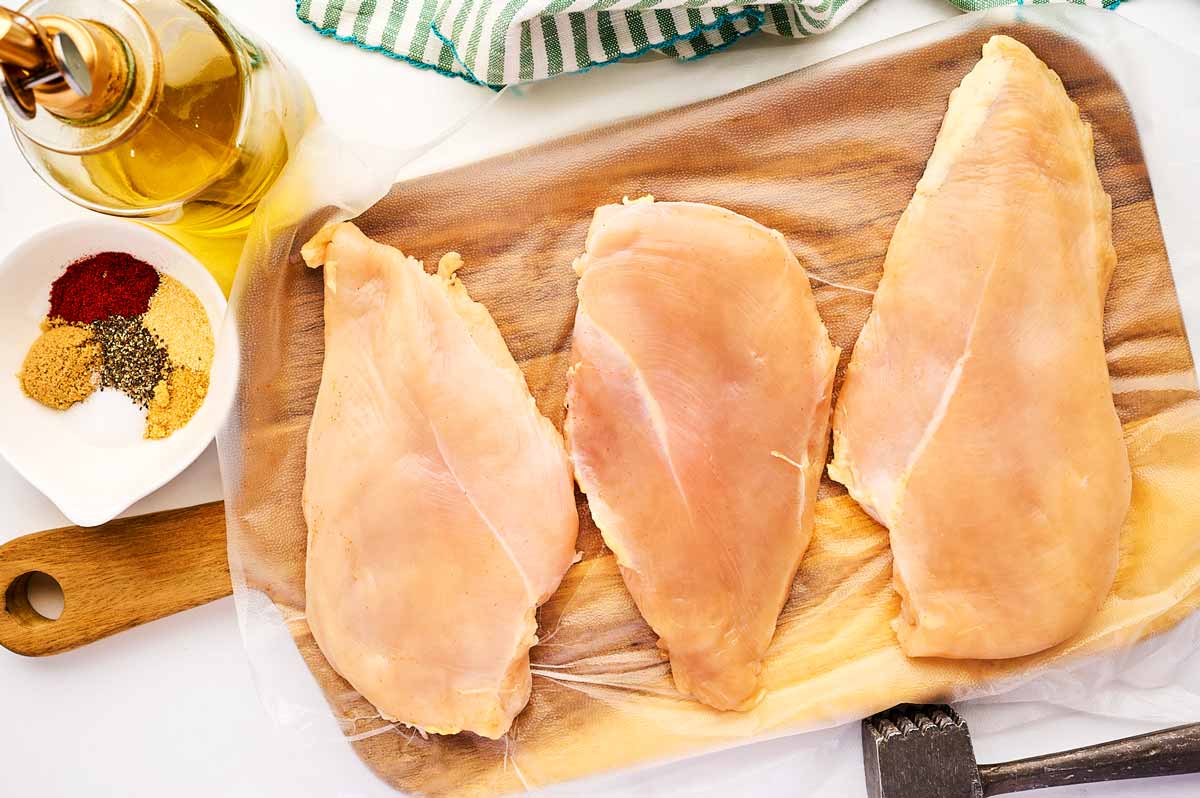 Pounding chicken breast with a meat mallet.