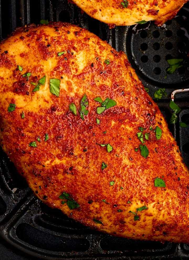 Air fried chicken breast in air fryer basket.