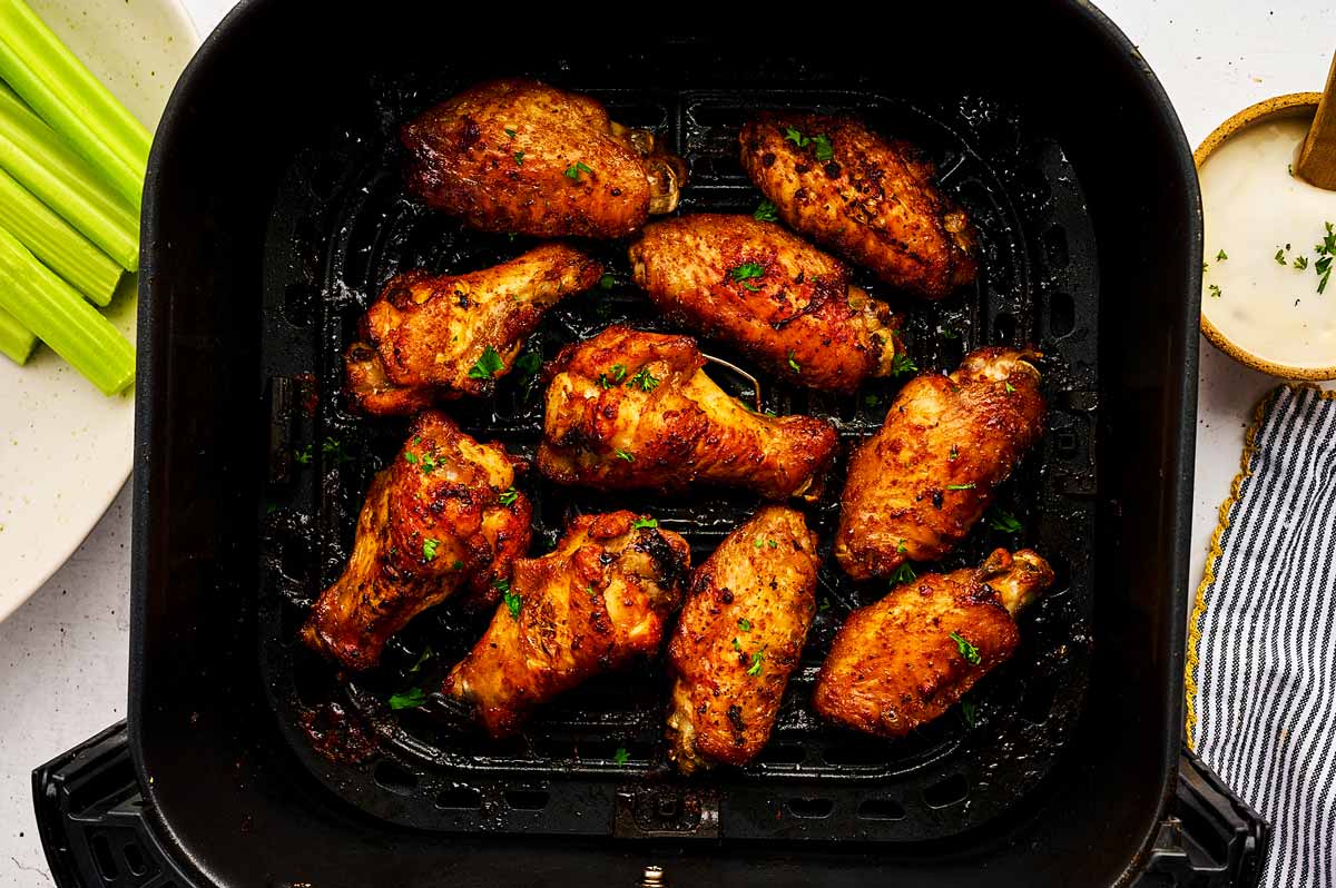 Air fryer basket with crispy chicken wings.