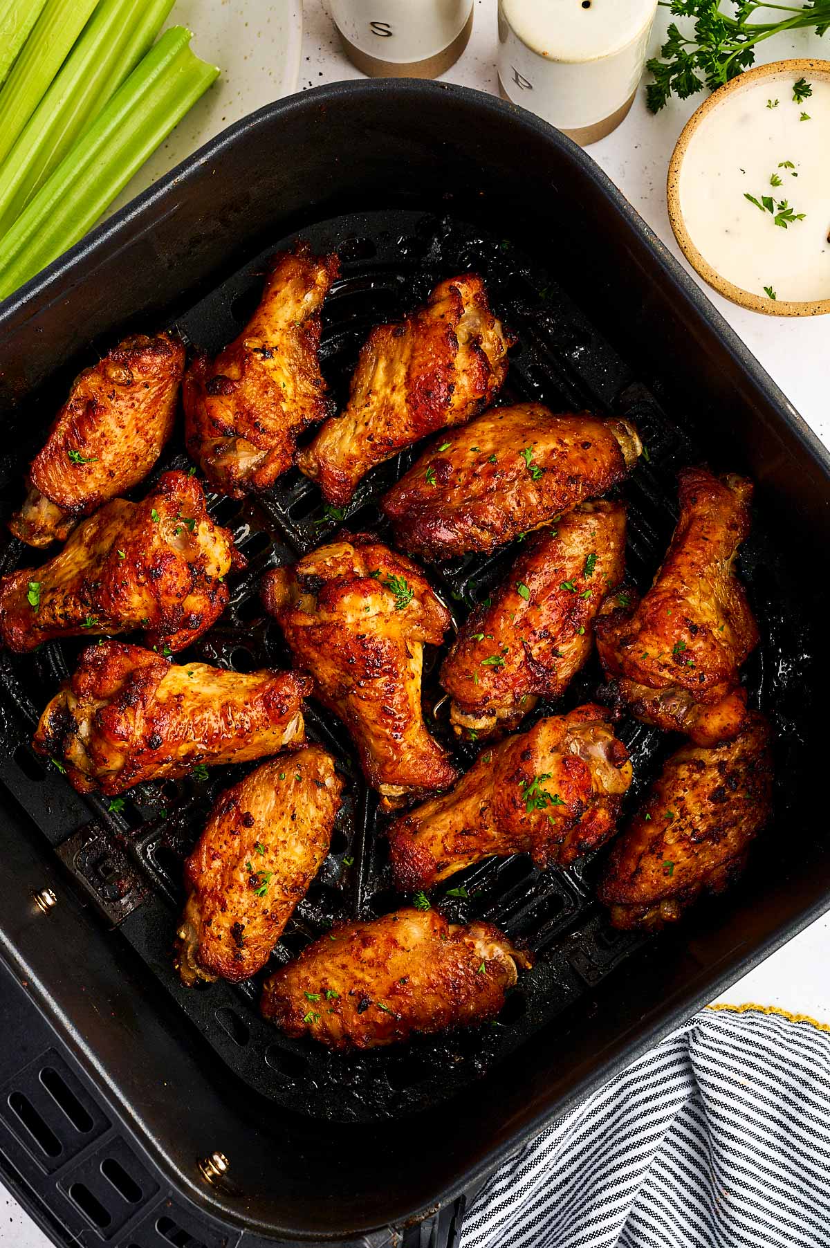 Air fryer basket with chicken wings.