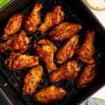 Air fryer basket with chicken wings.
