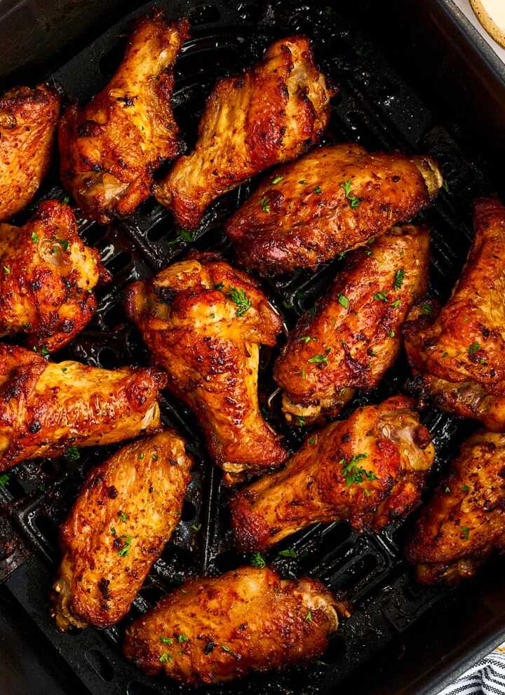 Air fryer basket with chicken wings.