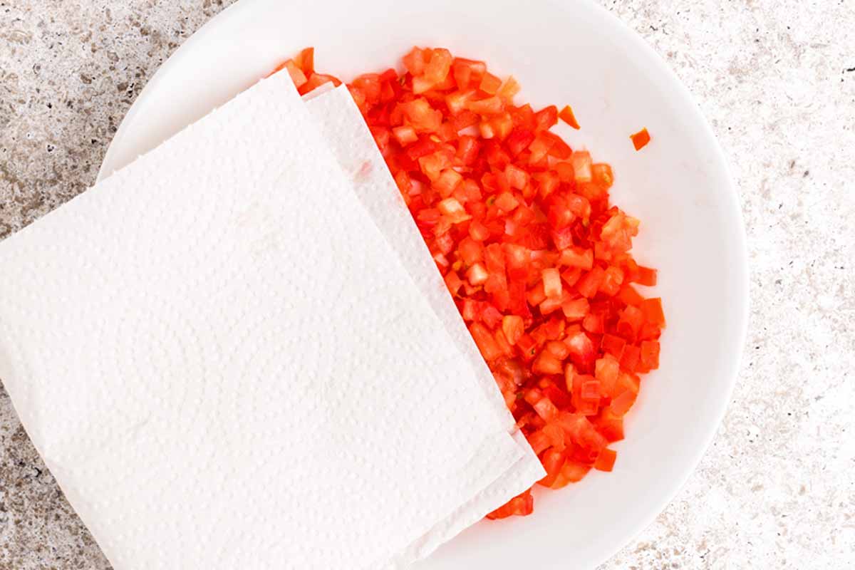 Blotting dry diced Roma tomatoes.