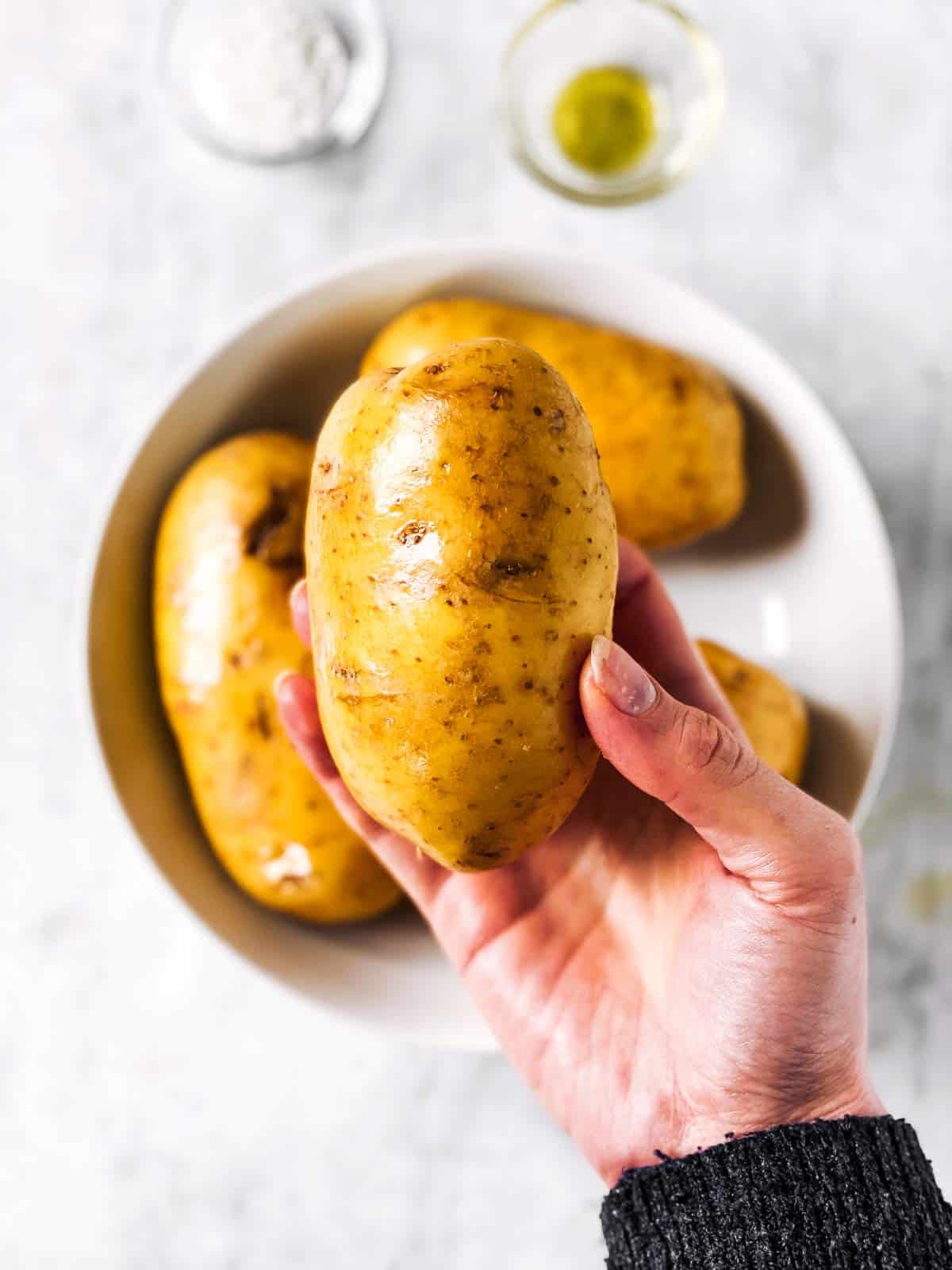 female hand holding an oil russet potato