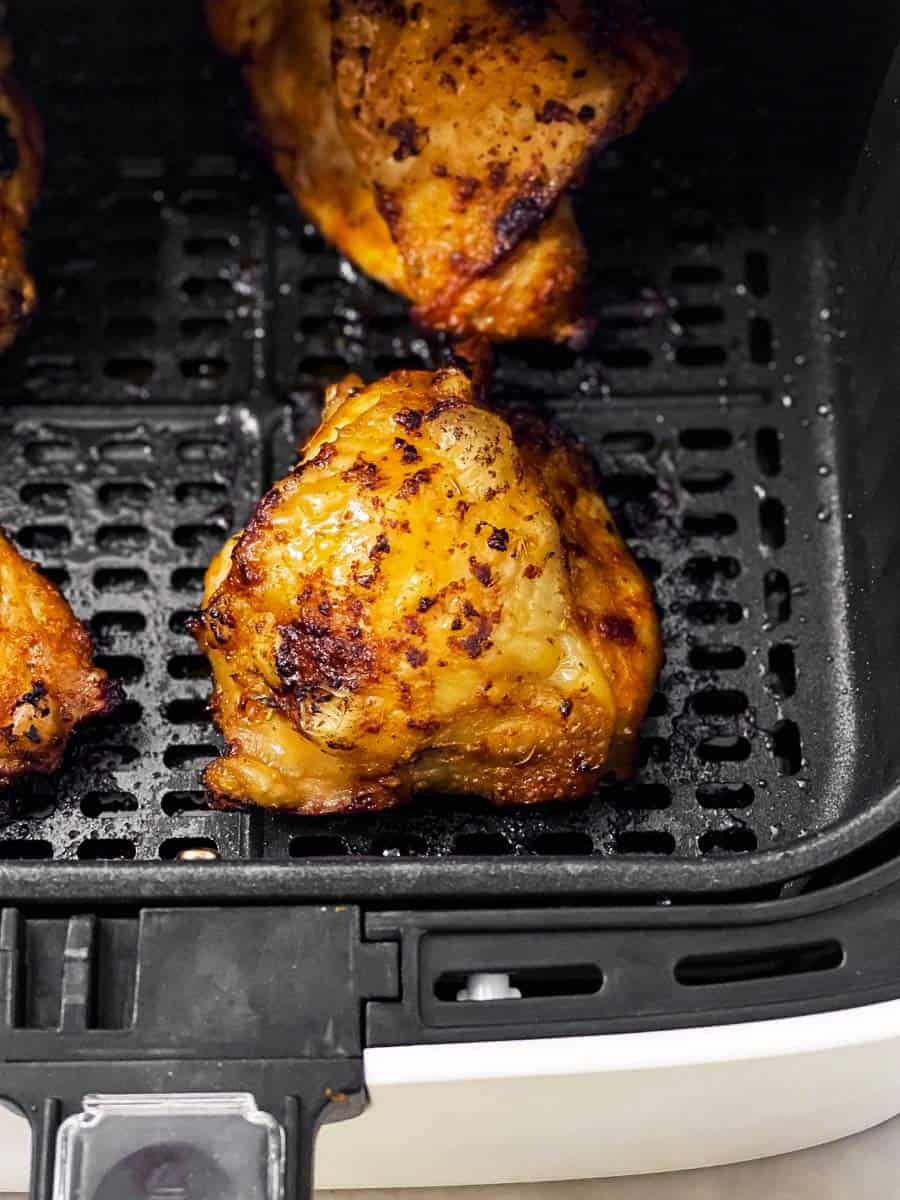 close up photo of crispy chicken thigh in air fryer basket