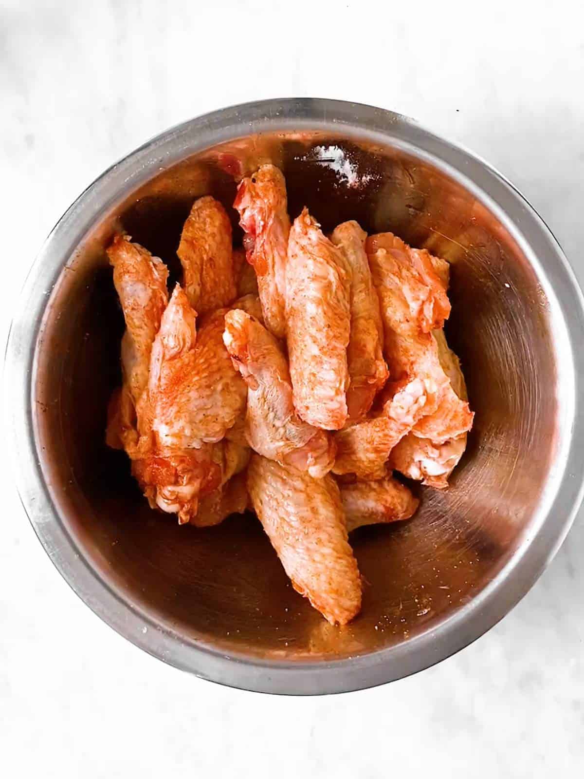 bowl with seasoned raw chicken wings