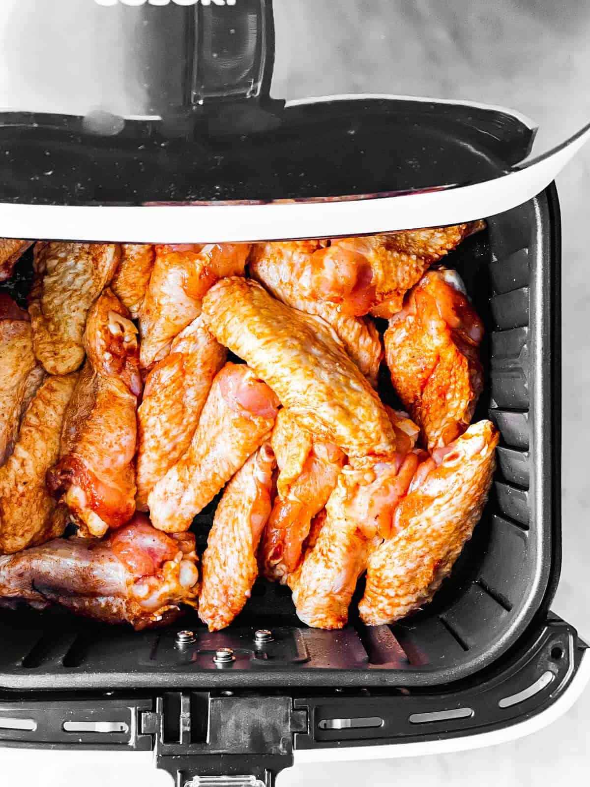 overhead view of raw chicken wings in air fryer basket