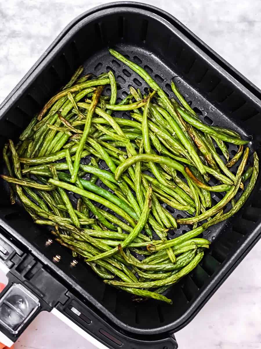 overhead view of air fryer basket filled with cooked green beans