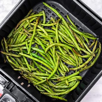 overhead view of air fryer basket filled with cooked green beans