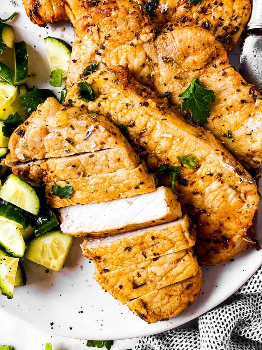 close up photo of sliced air fryer pork chop on plate with cucumber