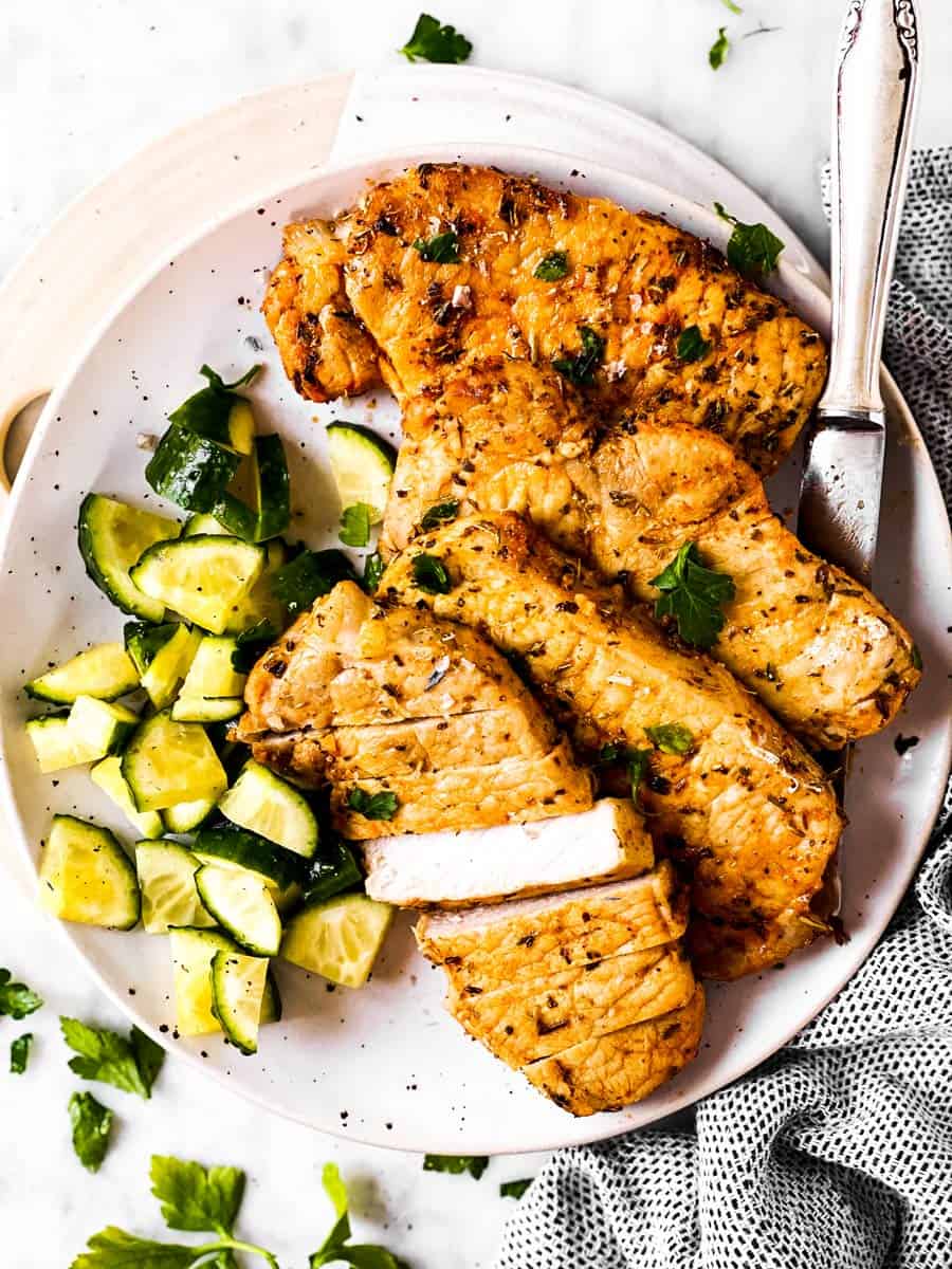 overhead view of pork chops with cucumber salad on white plate