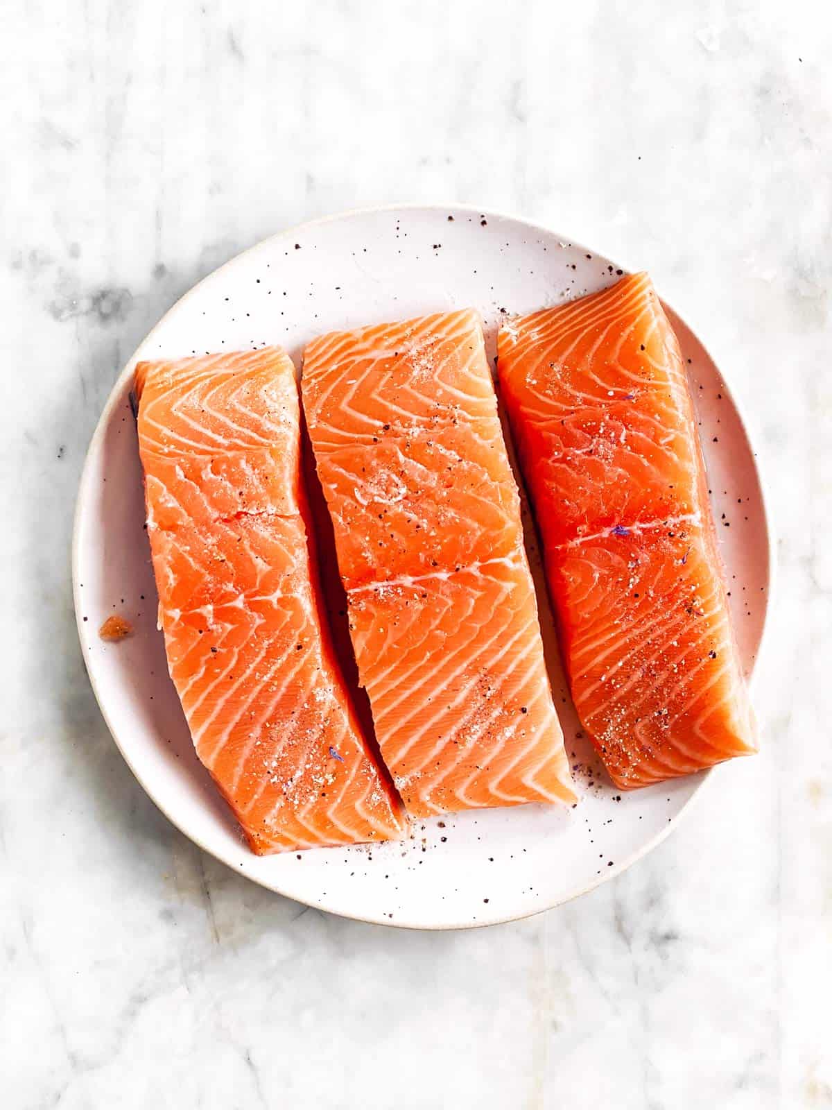 there raw salmon fillets on white plate