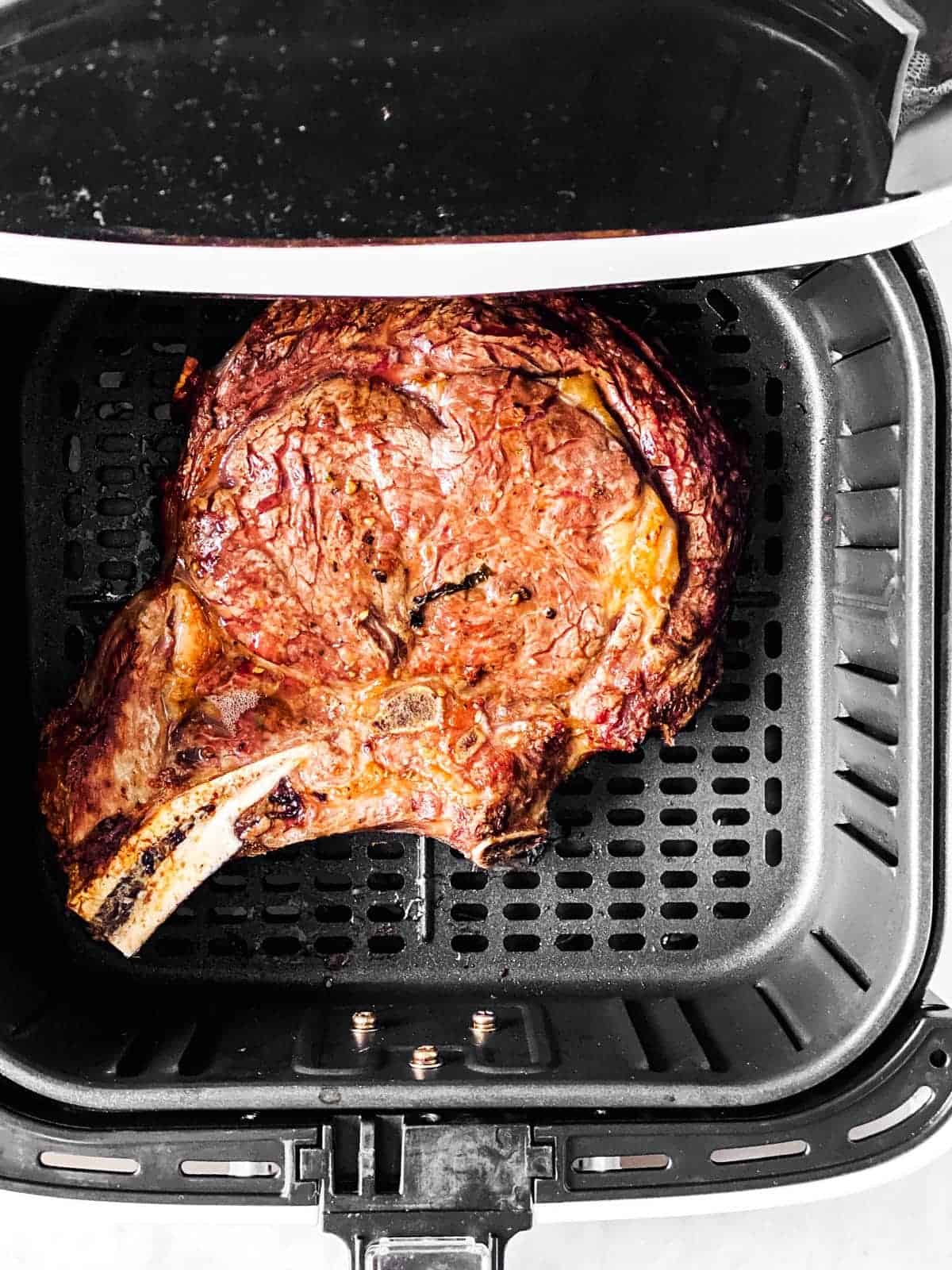 overhead view of cooked steak in air fryer basket