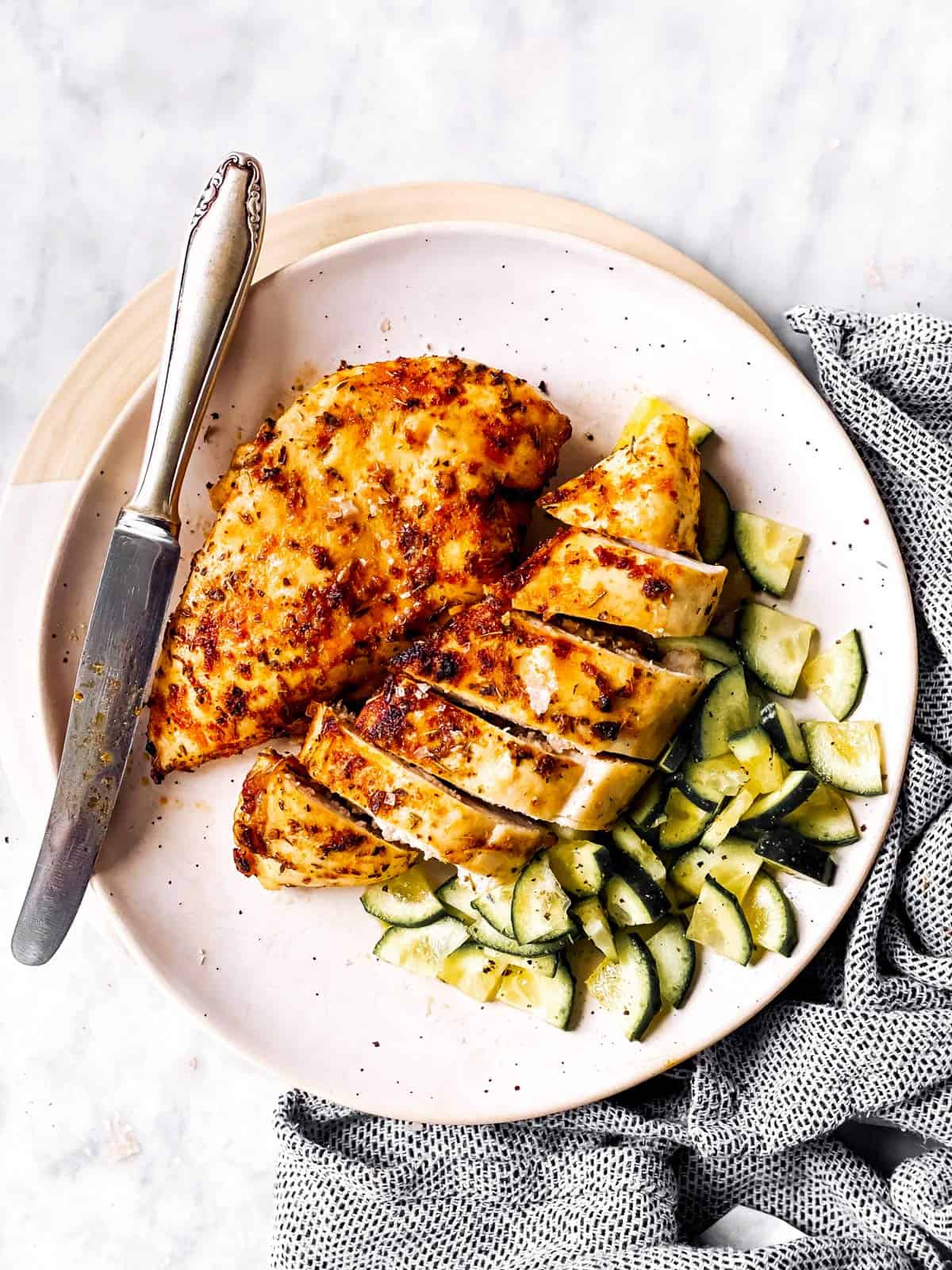 white plate with sliced chicken breast and cucumbers