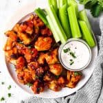 overhead view of white platter with buffalo cauliflower wings, ranch dip and celery sticks