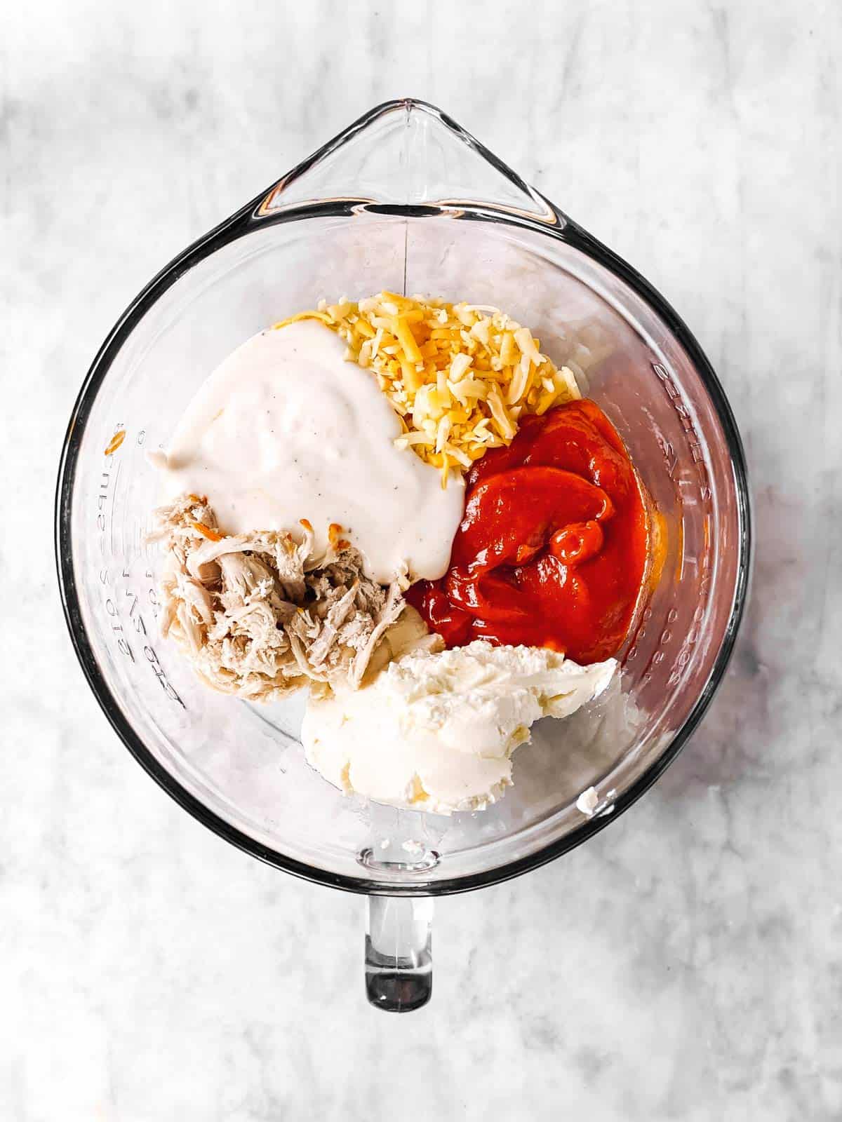 glass bowl with ingredients for buffalo chicken dip