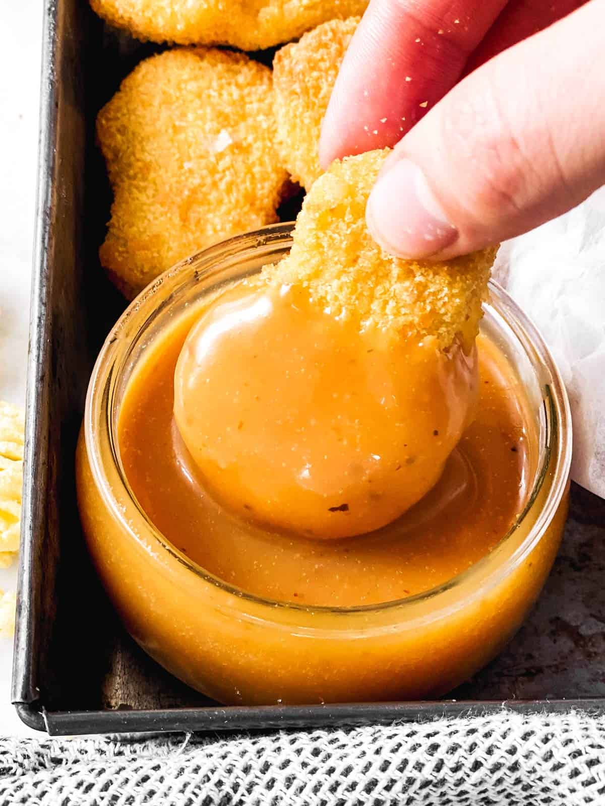 female hand dipping chicken nugget in copycat chick-fil-a sauce